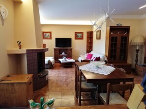 Una sala de estar con chimenea, televisor, mesa de comedor con sillas y sofá.