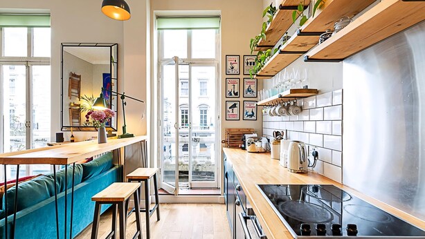 A modern kitchen with a central island, wooden countertops, and a built-in oven.