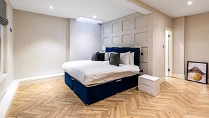 Une chambre à coucher avec un grand lit, une commode, une table de chevet et un tableau encadré au mur.