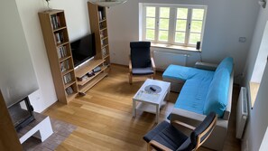 A living room with a TV, bookshelves, a sofa, and a window.