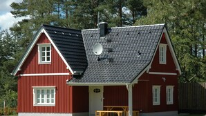 A red wooden house with a black roof, a satellite dish, and a wooden bench outside. - Cottage Faflik - Air Con And Own Sauna, Swedish house no 001 (Vlkov)