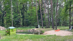 A forested area with a small green playhouse, a picnic table, and orange inflatable tubes. - Cottage Faflik - Air Con And Own Sauna, Swedish house no 001 (Vlkov)