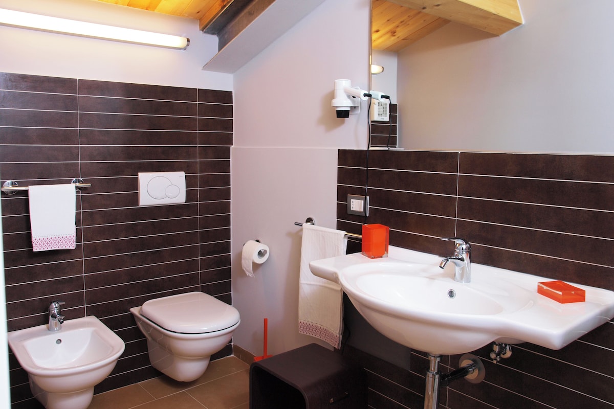 A bathroom with a bidet, toilet, sink, and mirror.