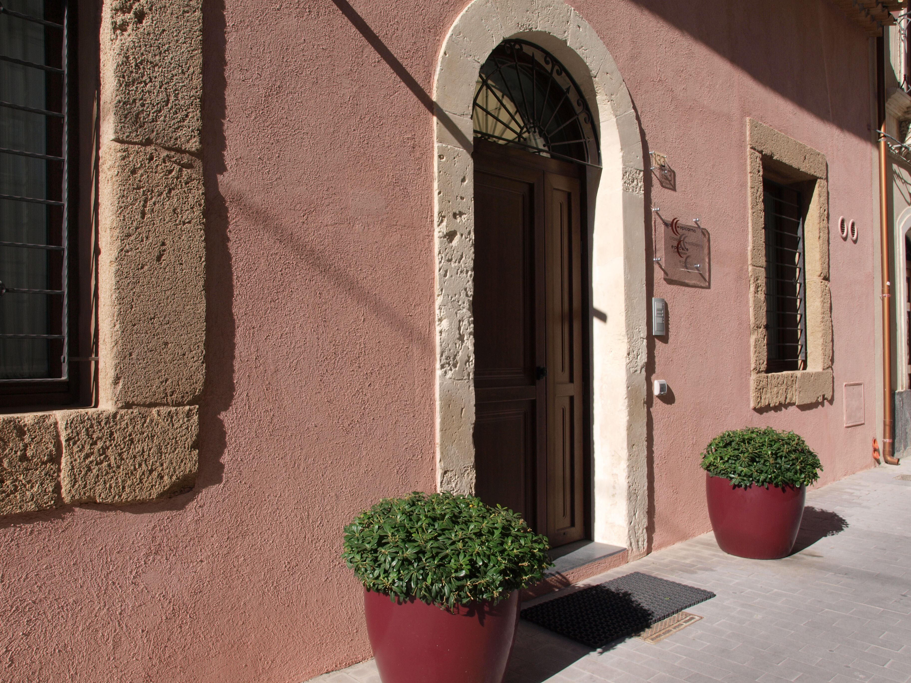 A building facade with a wooden door, a window with bars, and a potted plant.
