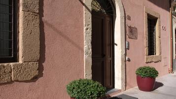 A building facade with a wooden door, a window with bars, and a potted plant.