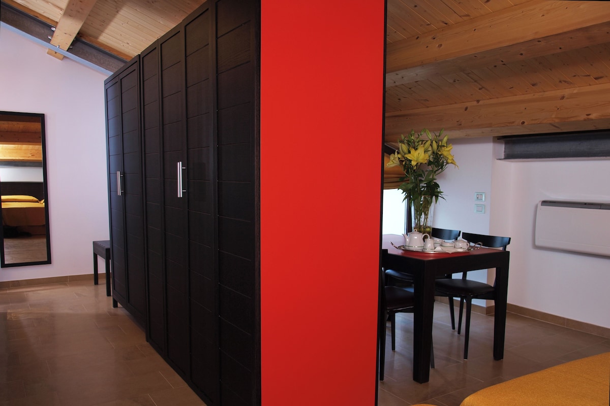 A modern room with a large wardrobe, a dining table with chairs, and a yellow sofa.