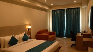 Habitación de hotel con una cama grande, un escritorio, una silla y un televisor.