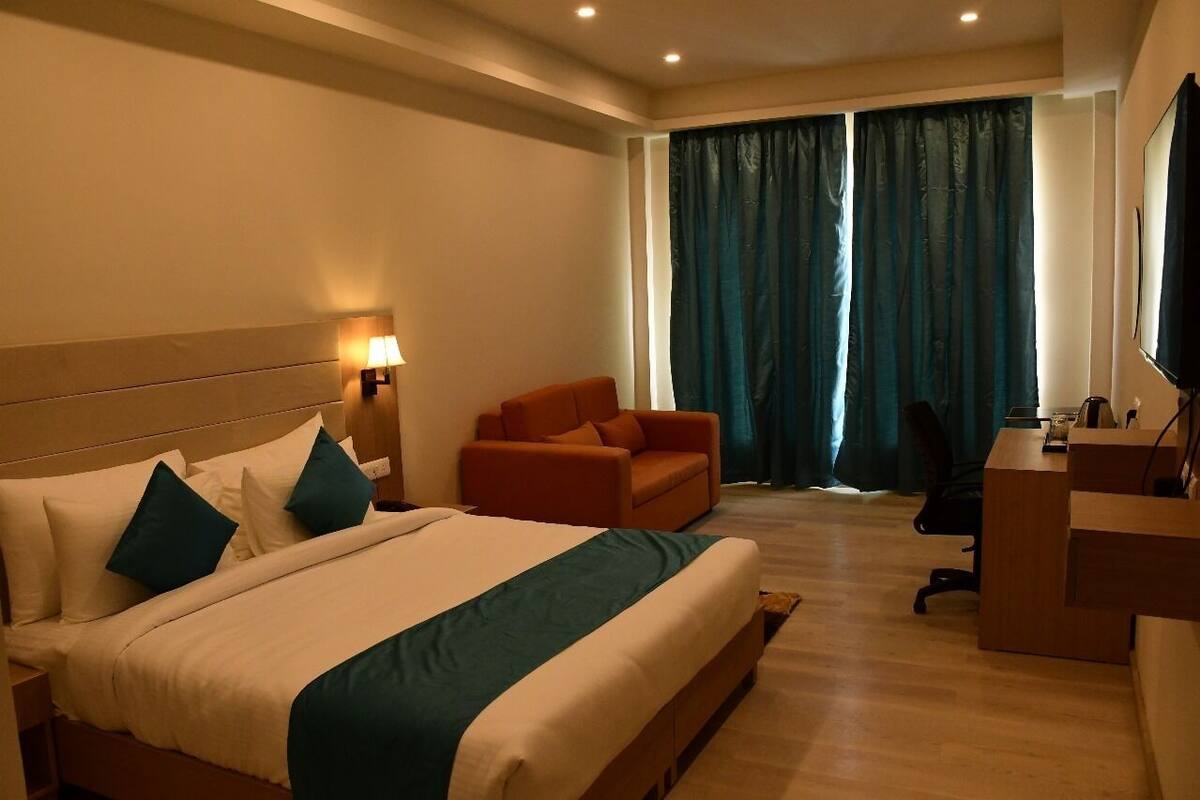 Habitación de hotel con una cama grande, un escritorio, una silla y un televisor.