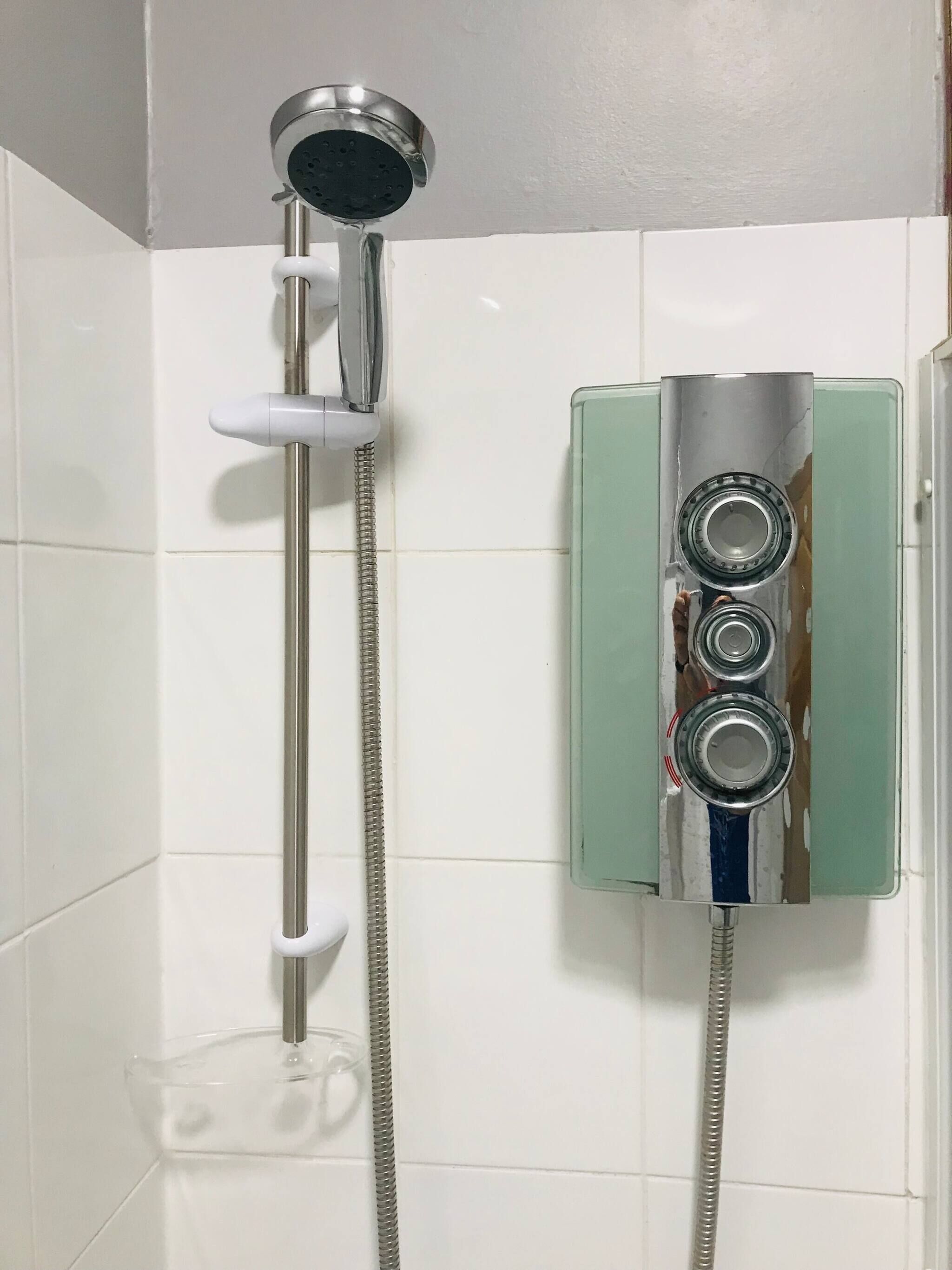 A shower with a handheld showerhead and a wall-mounted faucet.