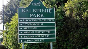 A sign listing attractions at Balbirnie Park, including the Rhododendron Collection, Woodland Walks, Bridle Path, Balbirnie Craft Centre, Balbirnie Golf Course, and Caravan Club Site.