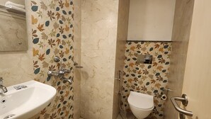 A bathroom with a sink, toilet, and shower. - Shamuka Hotel (Puri)