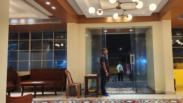 A hotel lobby with a reception desk, seating area, and a glass door entrance. - Shamuka Hotel (Puri)