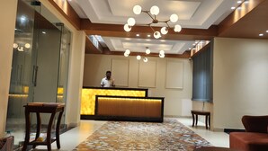 A hotel reception area with a modern design, featuring a reception desk, seating area, and a patterned rug. - Shamuka Hotel (Puri)