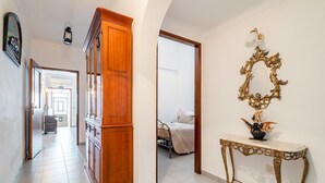 A hallway with a wooden cabinet, a mirror with an ornate frame, and a bedside table with a vase. - Teixeira 's House (Tavira)