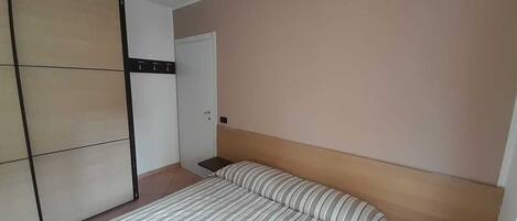Un dormitorio con cama, armario y puerta.