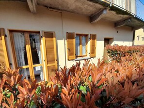 A building with multiple windows and shutters, surrounded by plants.
