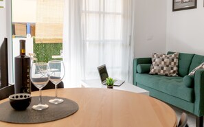A modern living room with a green sofa, a laptop on a small table, and two wine glasses on a round table. - Casa Frida Corralejo Centre, Fibre Wi-Fi, Bars, Restaurants & Shops Nearby (Corralejo)
