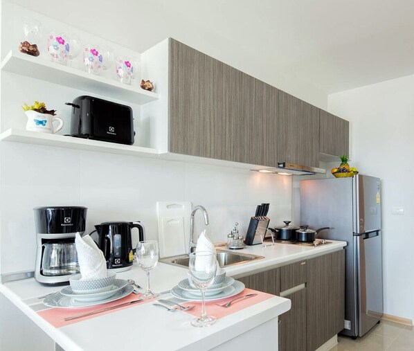 A modern kitchen with a built-in oven, a coffee maker, and a refrigerator.