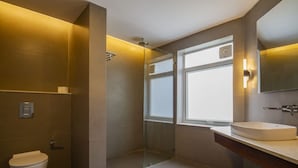 A modern bathroom with a glass-enclosed shower, a toilet, and a sink with a mirror above. - The Kaal (Leh)