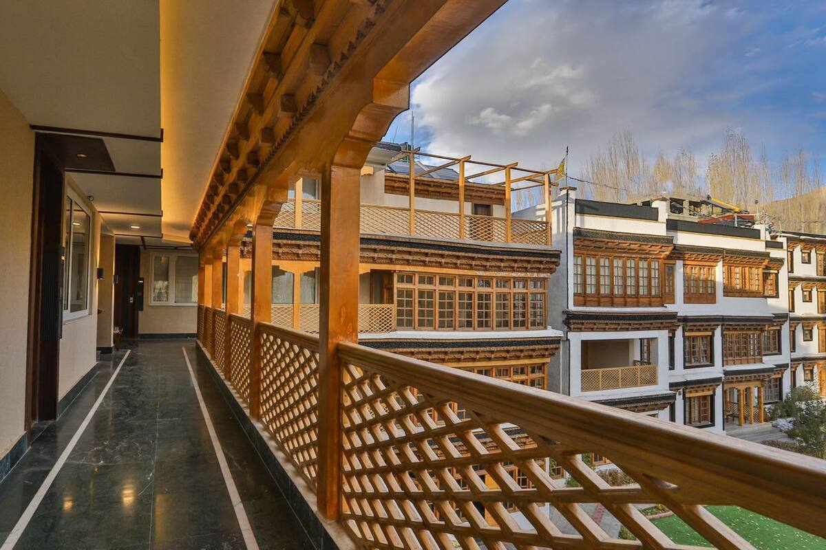 A corridor with a wooden railing, leading to a building with traditional architecture.