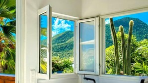 A kitchen with a window view of a mountainous landscape and cacti.