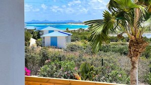 A view of a coastal area with a clear sky, a beach, and a small building with a blue roof.