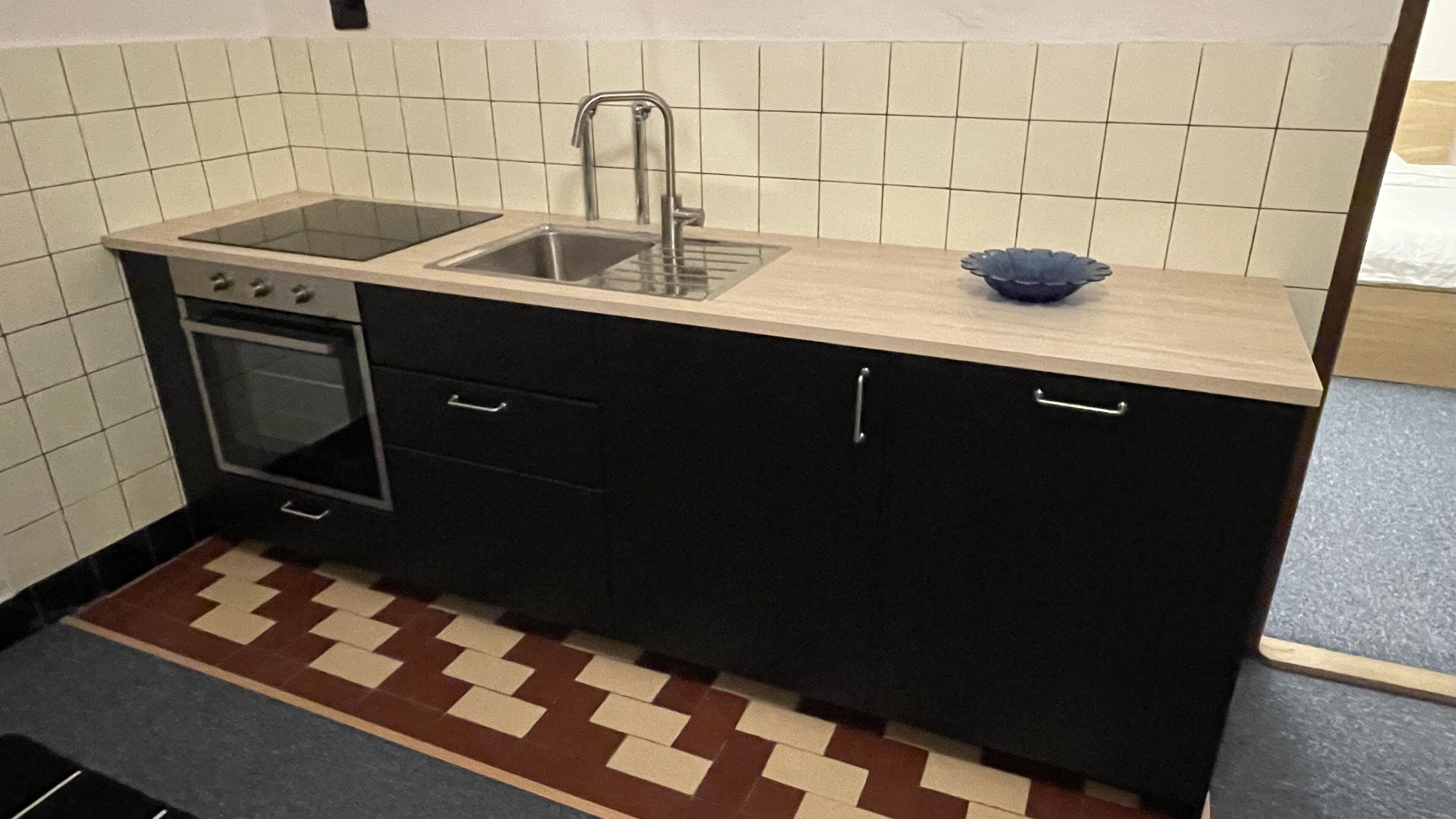 A kitchen with a sink, stove, and cabinets.