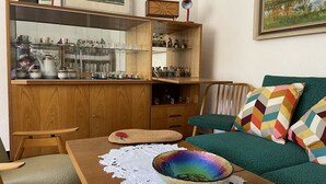 Un salón acogedor con un aparador de madera, un sofá verde y un cojín colorido.