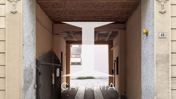 A building entrance with a decorative archway, a gated driveway, and a number sign indicating the address. - Suite Cavour by icasamia.it (Varese)