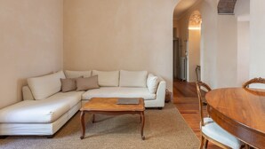 A living room with a sectional sofa, a wooden coffee table, and a dining table with chairs. - Suite Cavour by icasamia.it (Varese)
