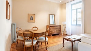 A dining area with a wooden table and chairs, a wooden cabinet, and a window with curtains. - Suite Cavour by icasamia.it (Varese)