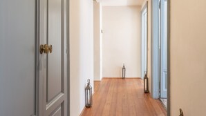A hallway with wooden flooring, grey doors, and a lantern on the floor. - Suite Cavour by icasamia.it (Varese)