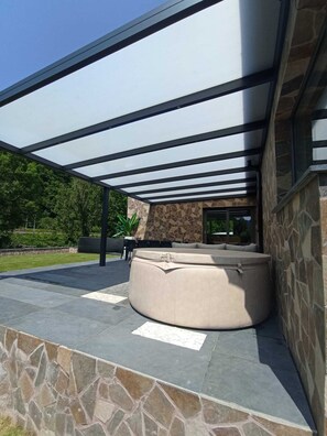 A modern outdoor seating area with a stone wall and a glass ceiling structure. - La Villa "les pieds dans l'eau" (Comblain-au-Pont)