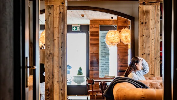 Un interior moderno con vigas de madera, un sofá y una zona de comedor.