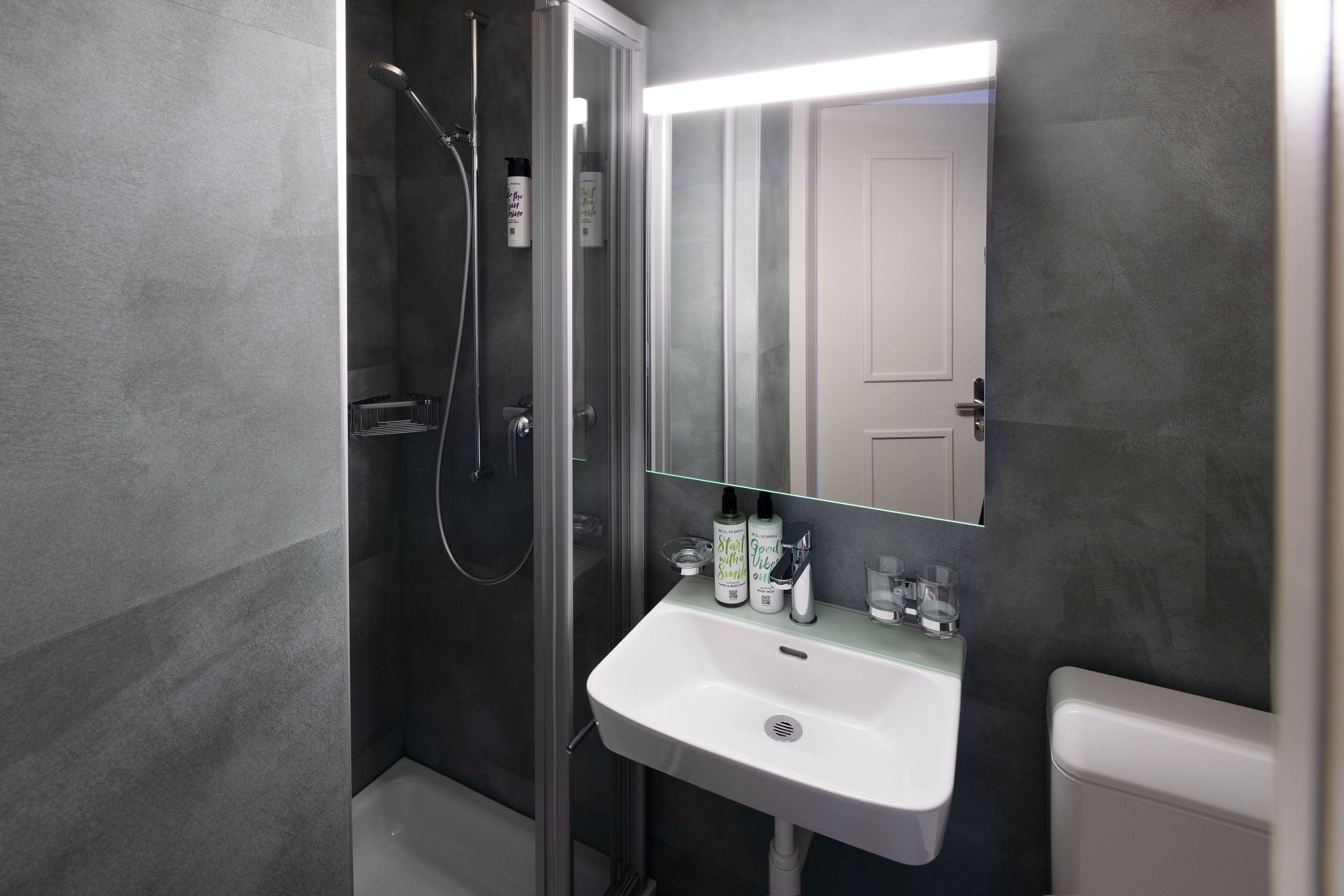 A modern bathroom with a glass-enclosed shower, a white sink, and a mirror above it.