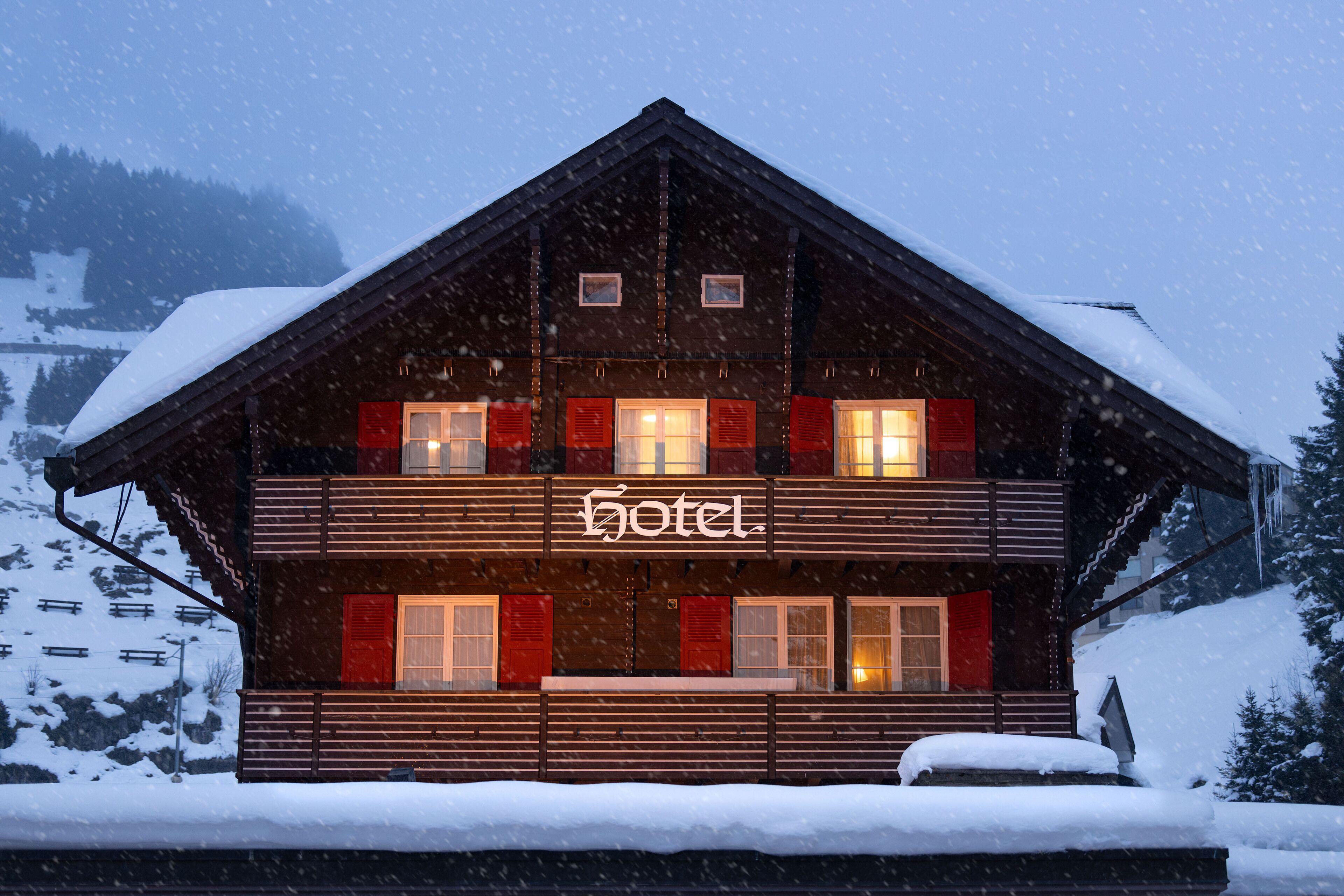 Ein Hotel aus Holz, in der Mitte ein Schild mit der Aufschrift "hotel", umgeben von Schnee.
