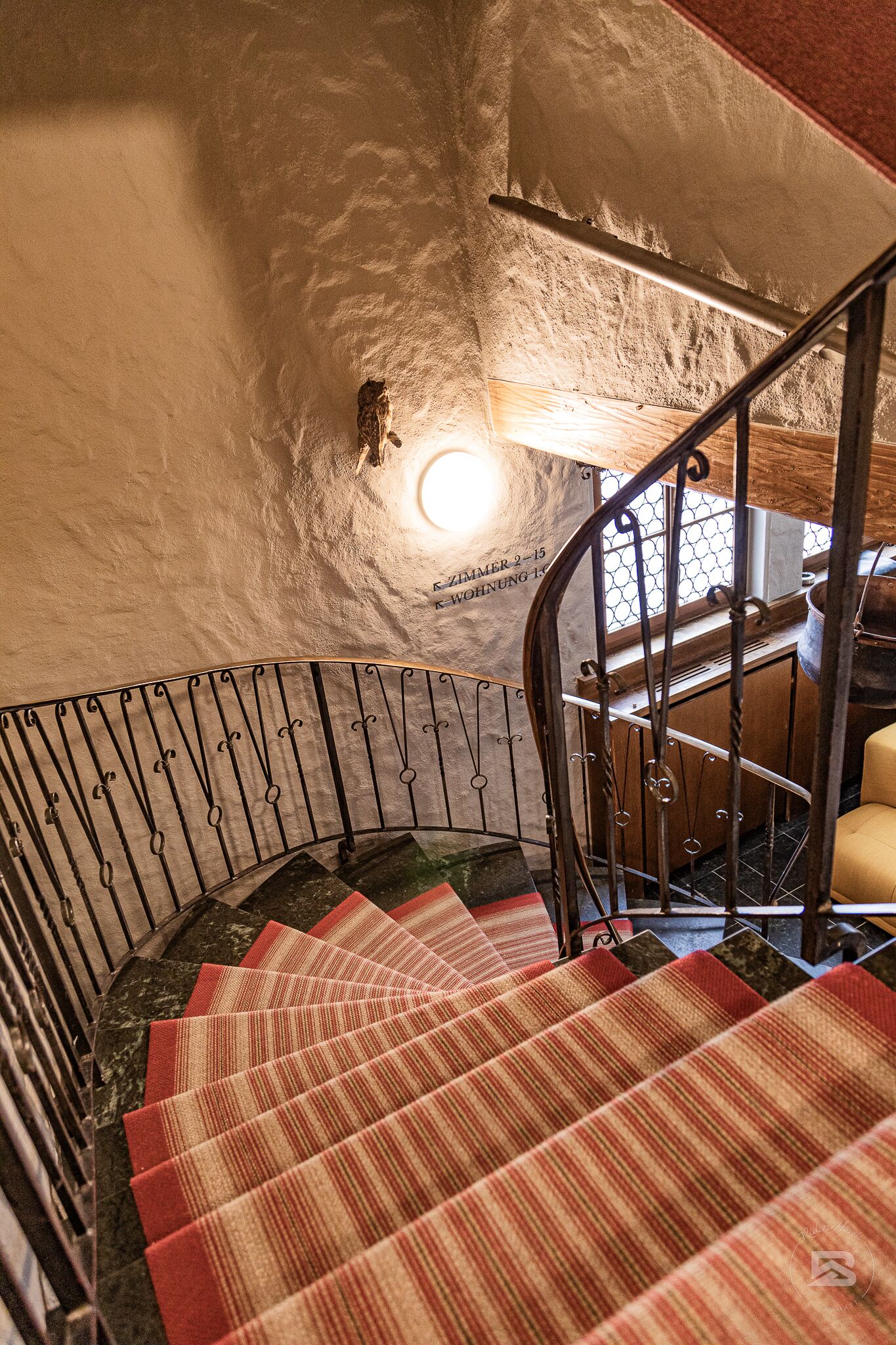 A spiral staircase with a metal railing and patterned carpet.