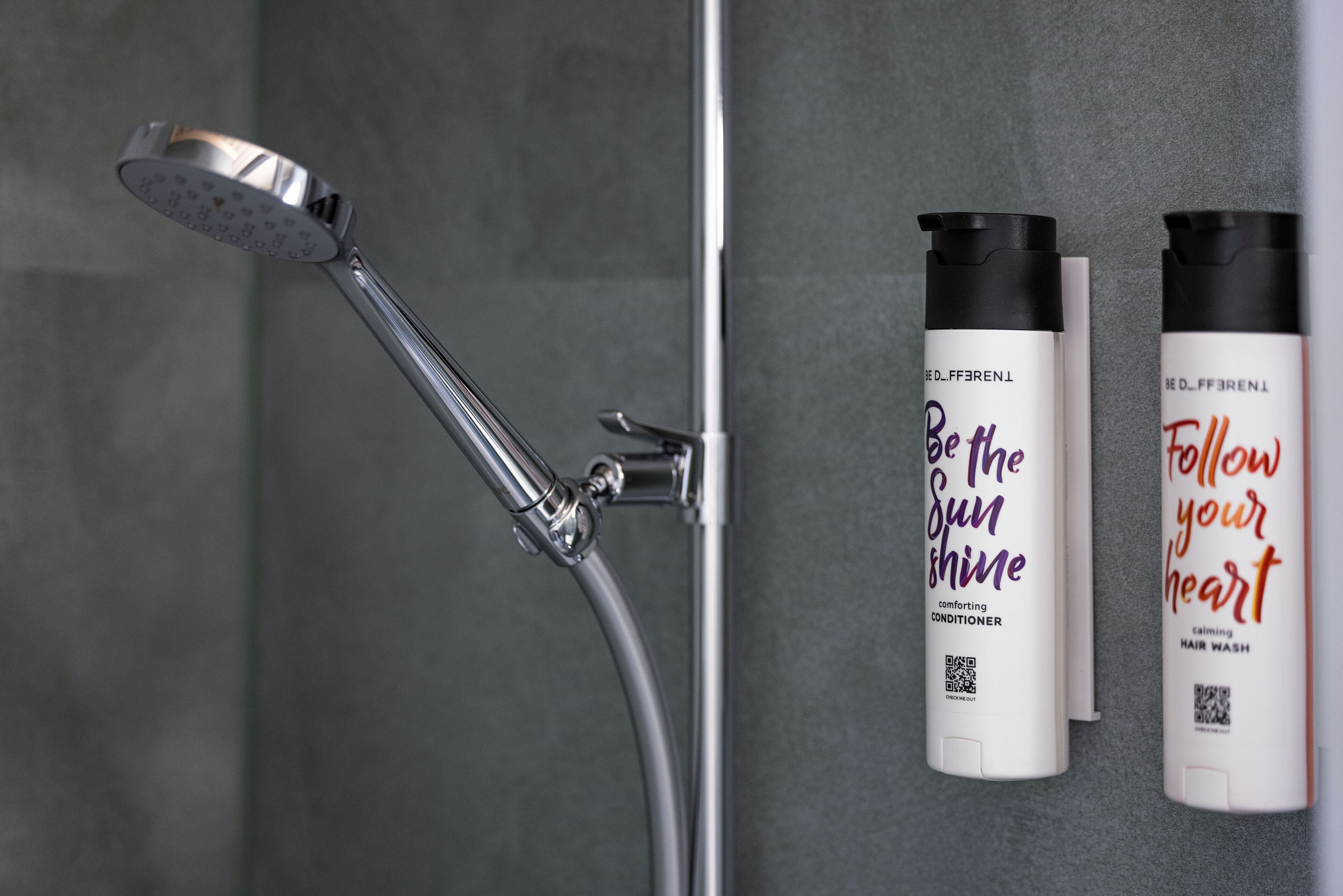 Un cabezal de ducha y dos botellas de productos para el cabello en una pared de baño.