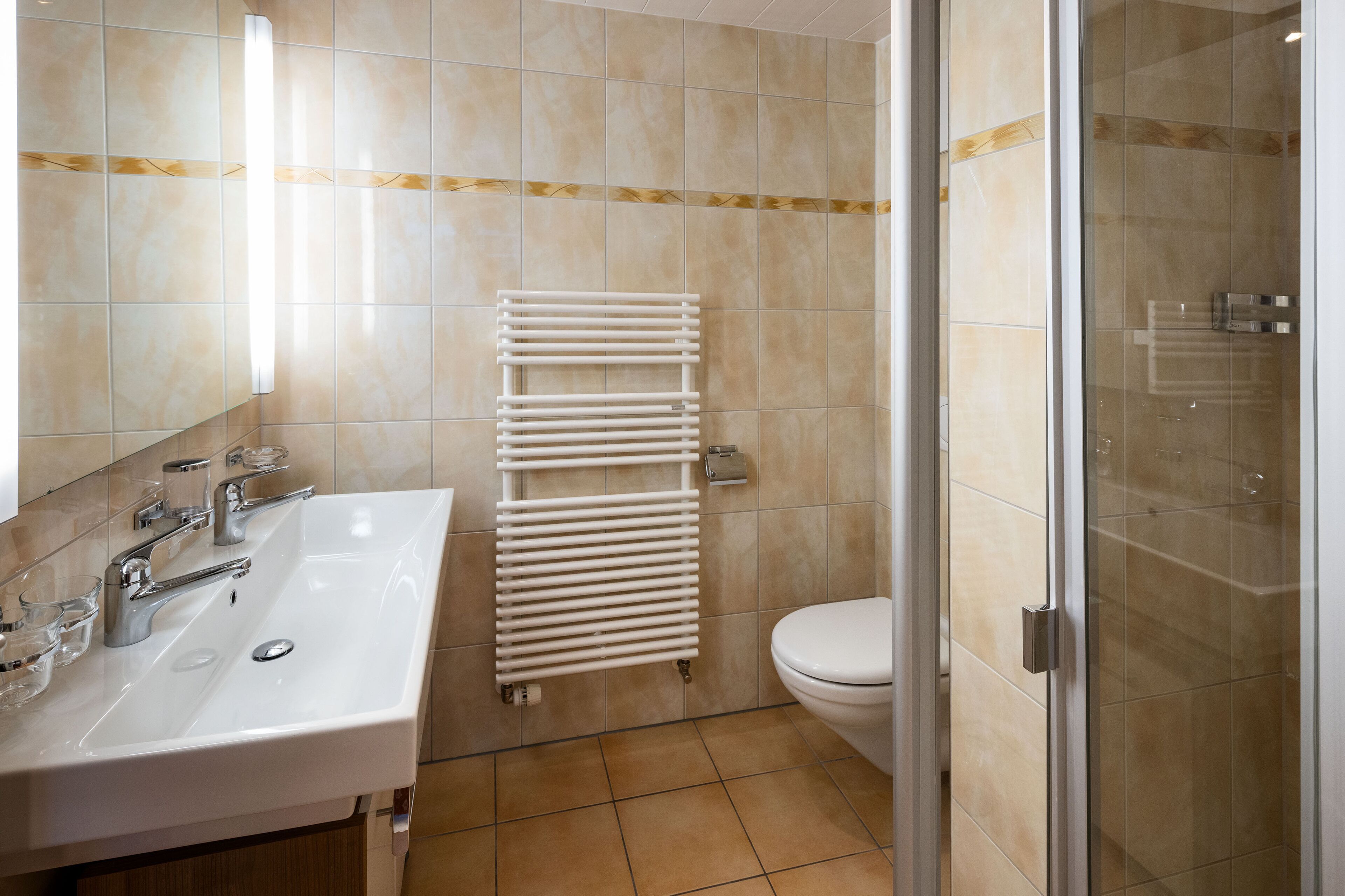 A bathroom with a white sink, mirror, and a glass shower enclosure.