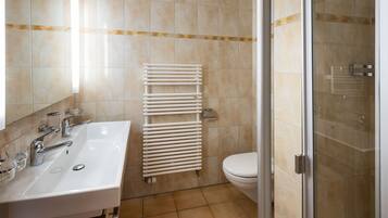 A bathroom with a white sink, mirror, and a glass shower enclosure.