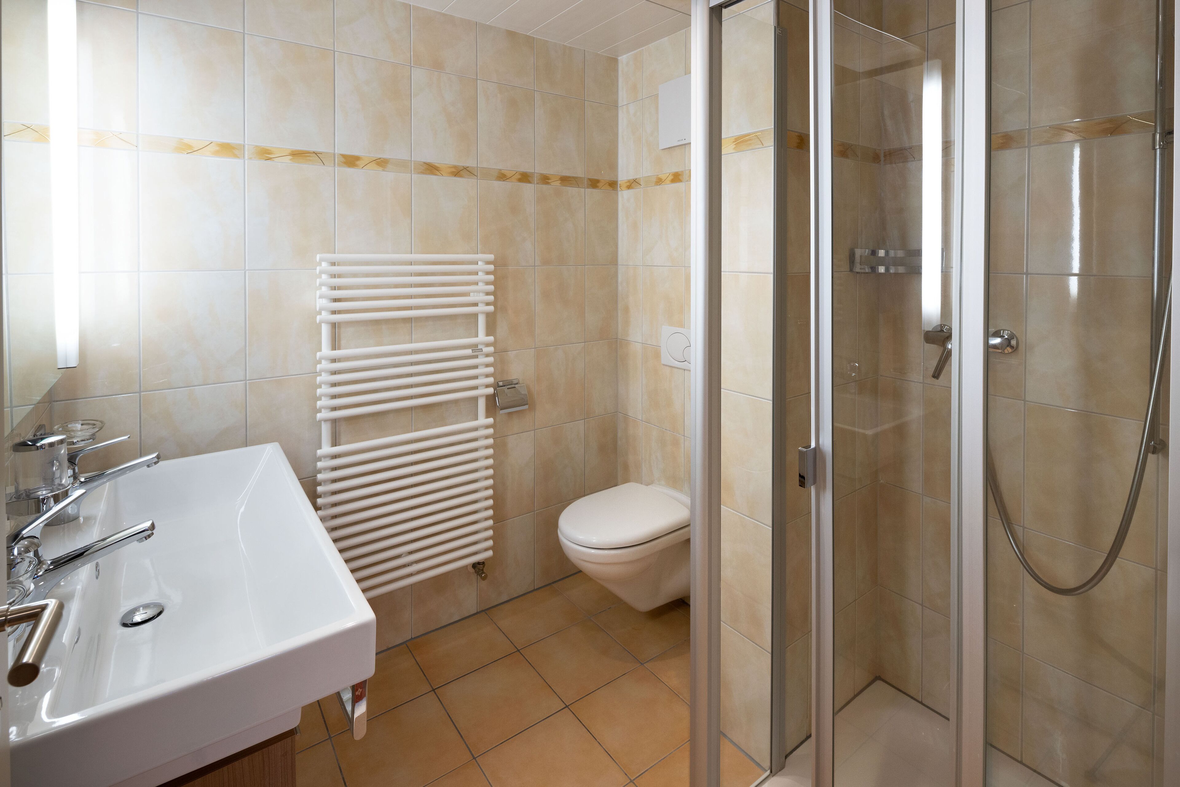 Un baño con un lavamanos blanco, un inodoro y una ducha con mampara de vidrio.