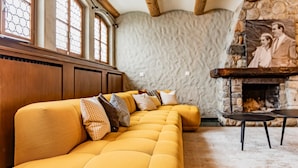 Un sofá amarillo con varios cojines, una chimenea de piedra y un techo de madera.