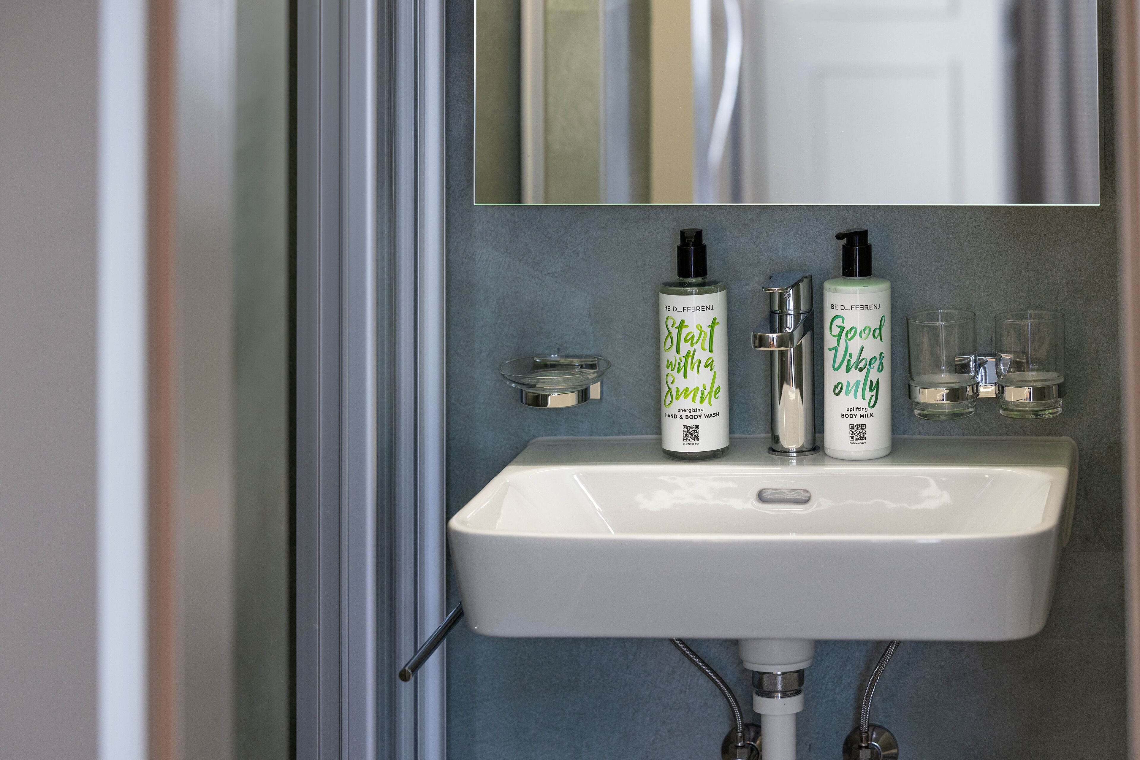 A bathroom sink with two bottles of body wash and a mirror above it.
