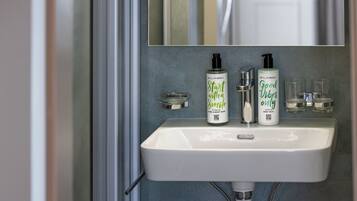 A bathroom sink with two bottles of body wash and a mirror above it.
