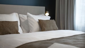 Una cama bien hecha con ropa de cama blanca y marrón, un cabecero y una lámpara de noche.