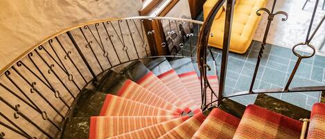 Eine Wendeltreppe mit einem rot-weiß gestreiften Teppich, einer Holzhandlauf und einem Metallgeländer.