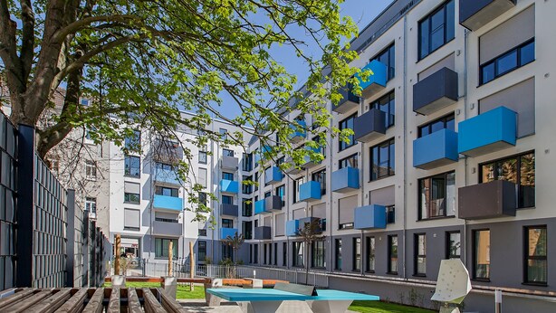 Un immeuble d’appartements moderne doté de balcons, d’une table de billard et d’un espace de détente extérieur.