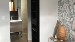 Une chambre d’hôtel moderne équipée d’un lit, d’une table de chevet avec une lampe, d’une armoire et d’une salle de bain avec un lavabo et un miroir.