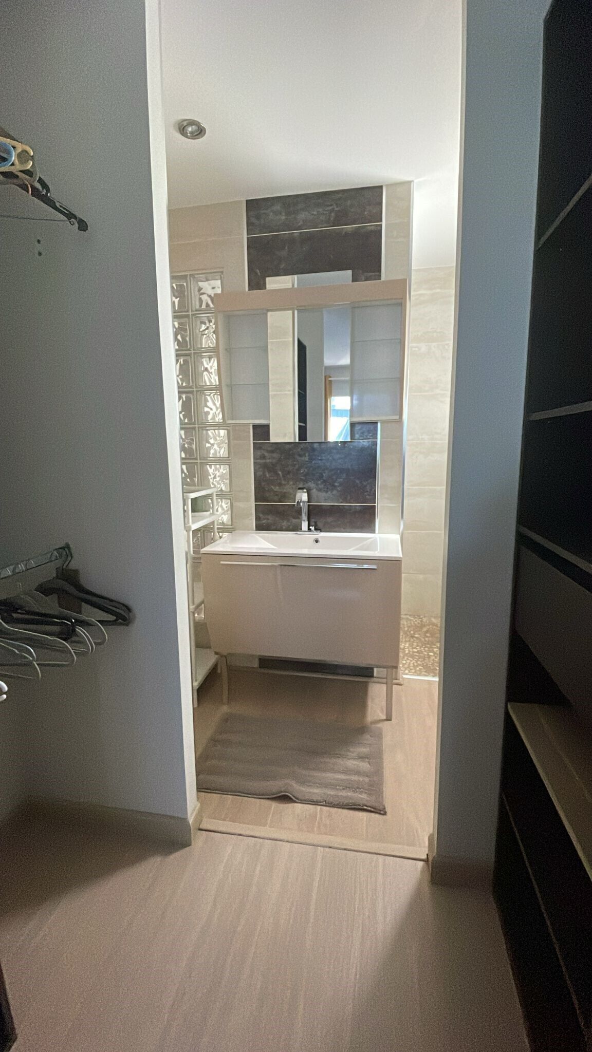 A modern bathroom with a large mirror, a sink, and a towel rack.