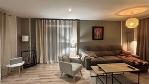 Un salon moderne comprenant un canapé, un fauteuil, une table basse et une lampe.